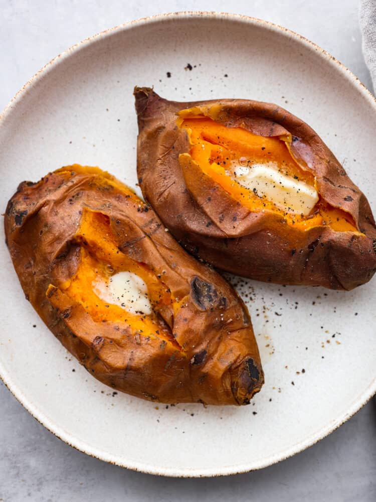 2 fully cooked sweet potatoes sliced open and served with butter and salt and pepper.