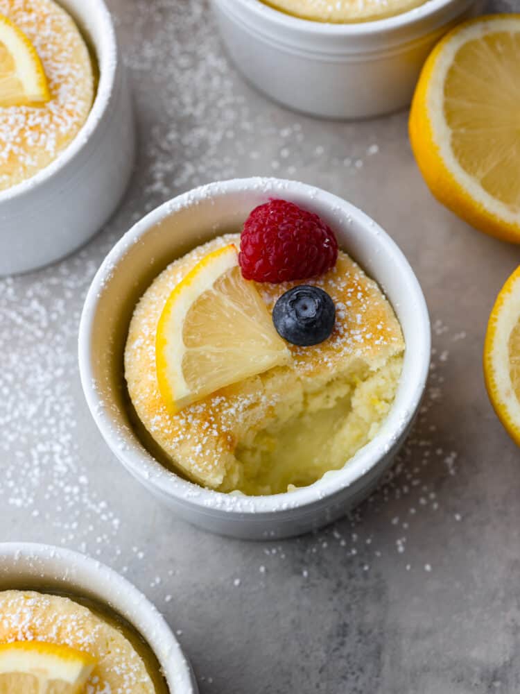 Lemon pudding cake in a ramekin with a bite taken out of it. 
