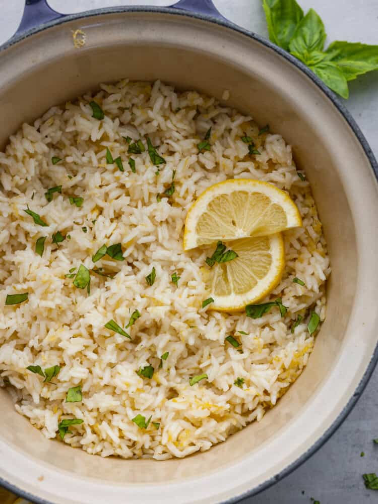 Lemon rice in a blue pot, garnished with lemon and herbs.