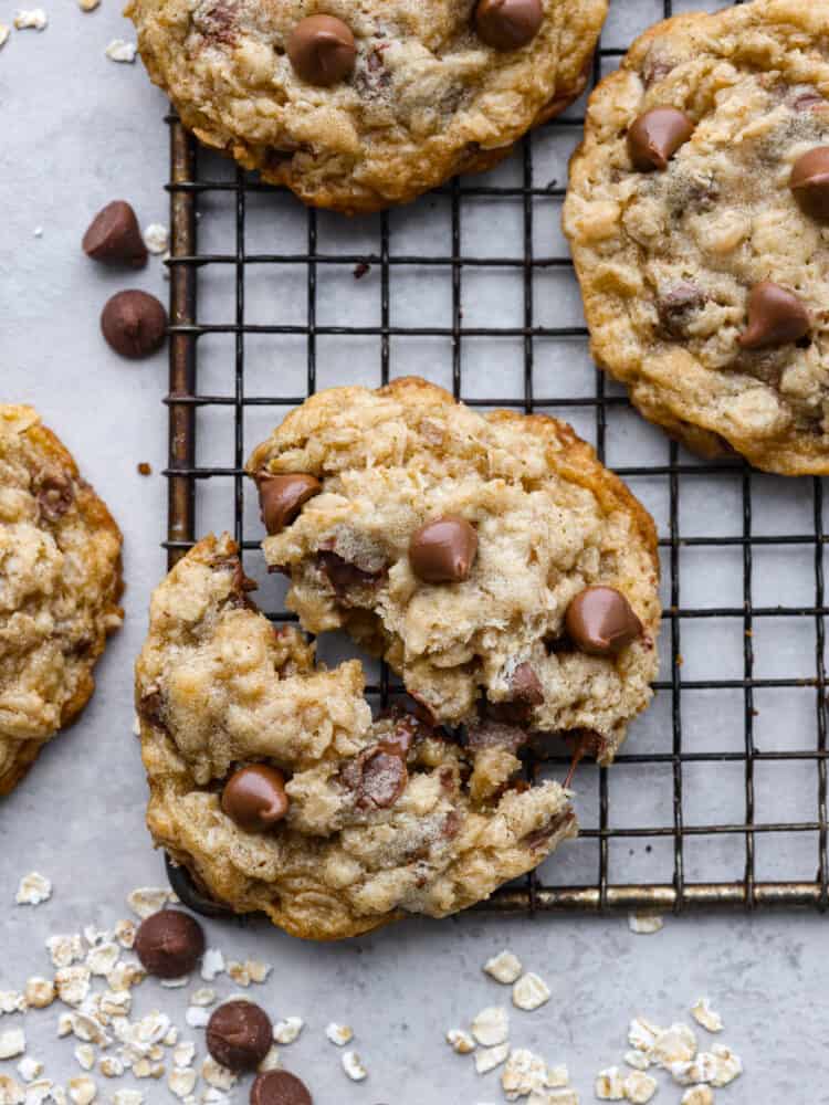 A close up of a oatmeal chocolate chip cookie on a cooling rack, broken in half. 