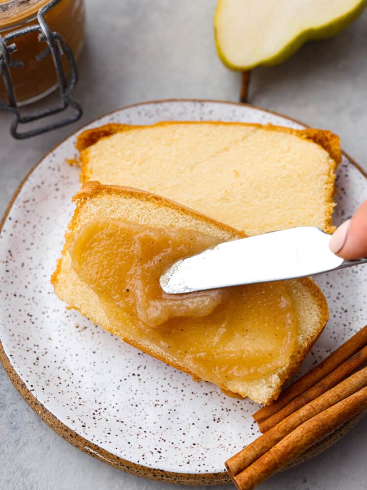Spreading pear butter on two slices of pound cake.