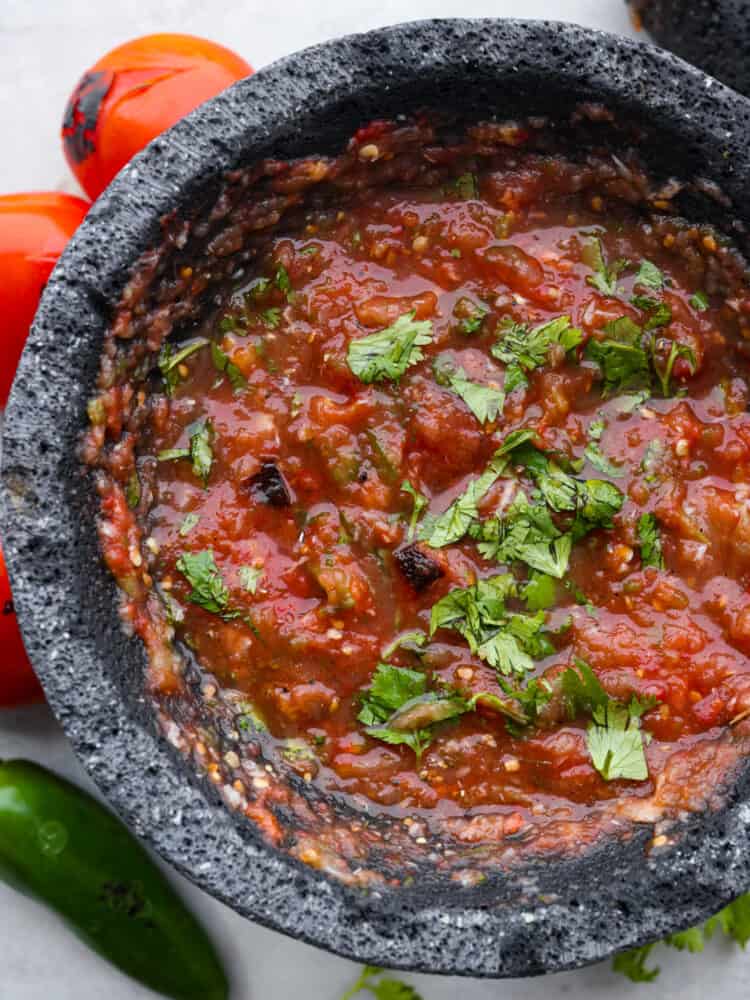 Roasted tomato salsa, garnished with chopped cilantro, in a molcajete.
