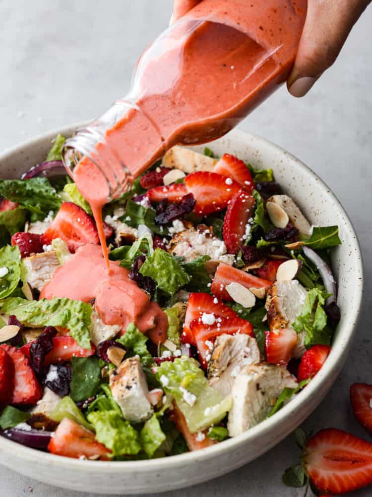 Strawberry vinaigrette being drizzled over the top of a salad. 