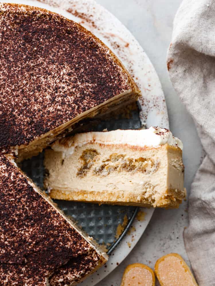 The topview of a tiramisu cheesecake with one slice laying on its side. 