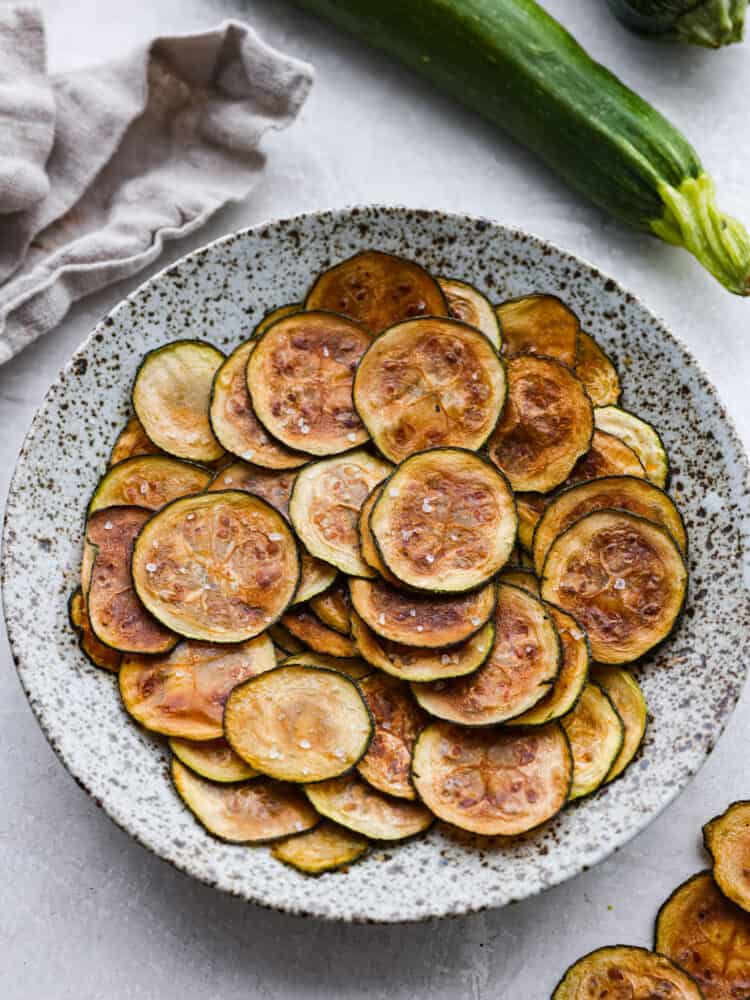 A speckled plate with zucchini chips on it. 
