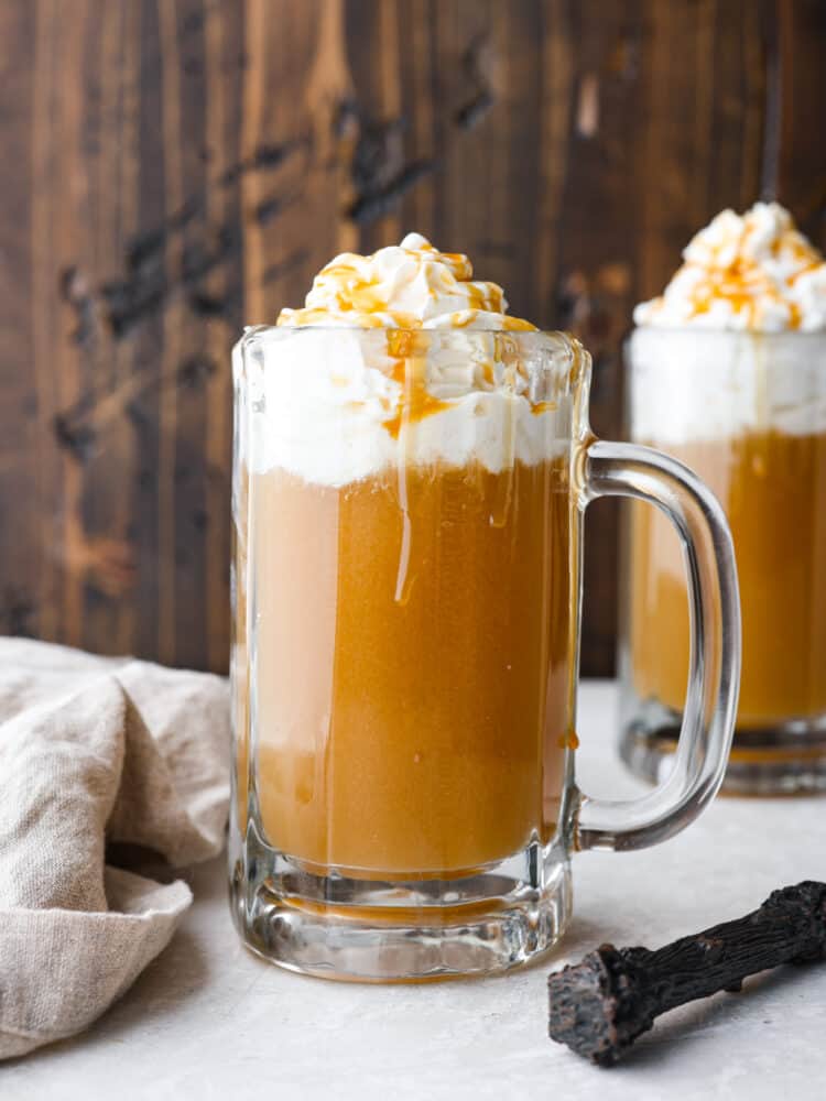 Butter beer in a glass mug, topped with whipped cream and caramel drizzle.
