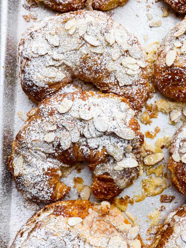 Top-down view of baked almond croissants topped with powdered sugar.