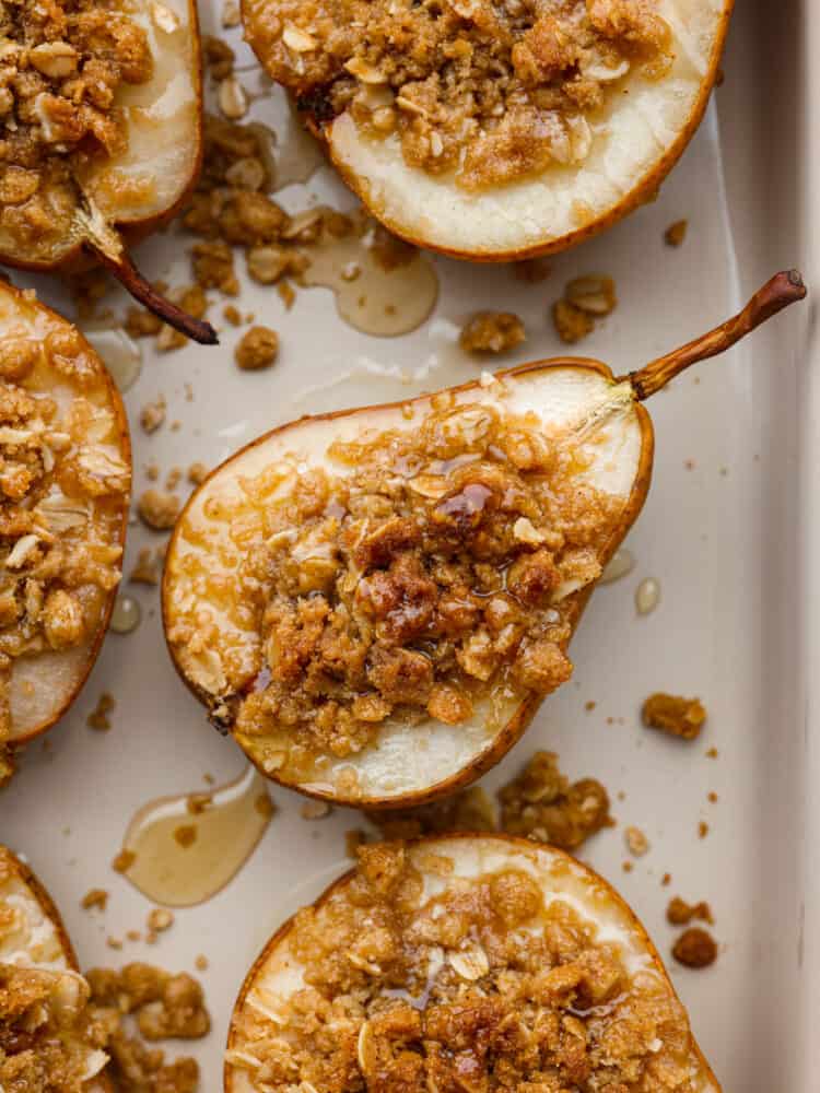 Closeup of a baked pear topped with oats, cinnamon, and brown sugar.