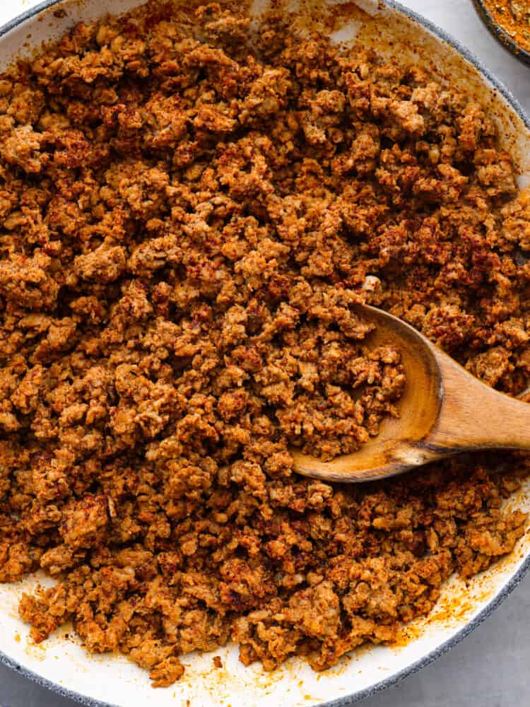 Mexican Chorizo ground pork in a pan with a wooden spoon.