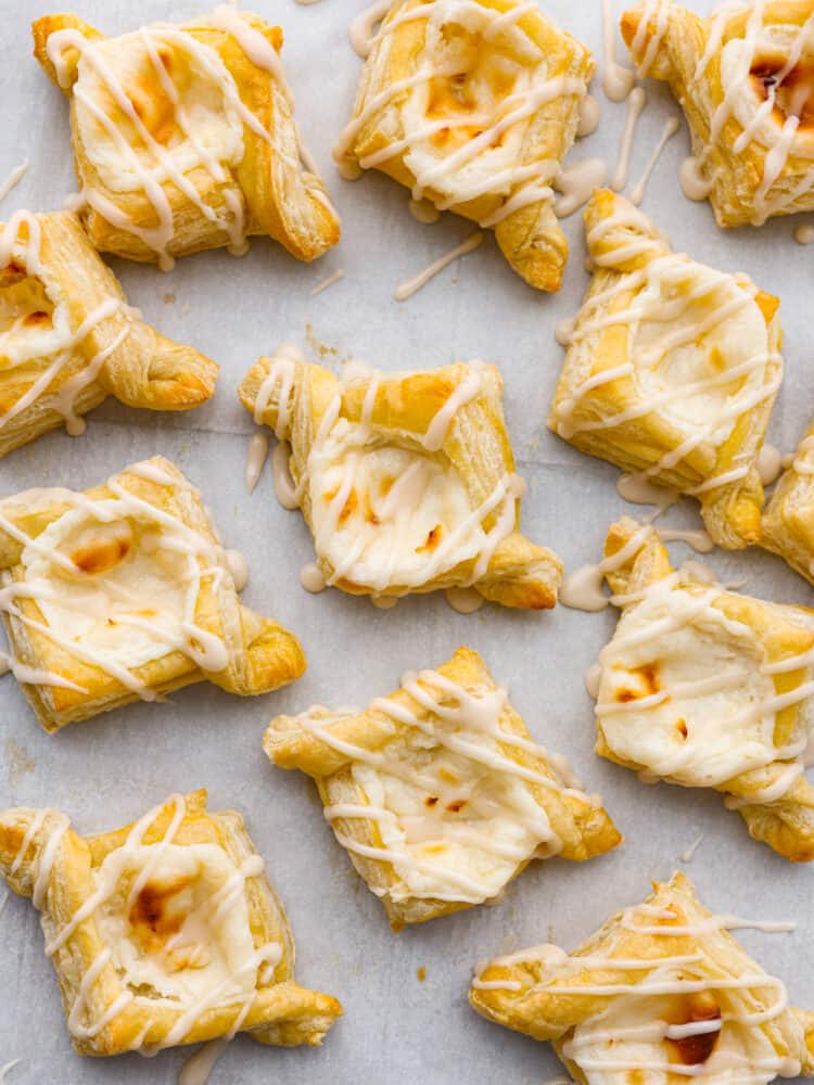 Closeup of baked cheese danishes laid out on parchment paper.