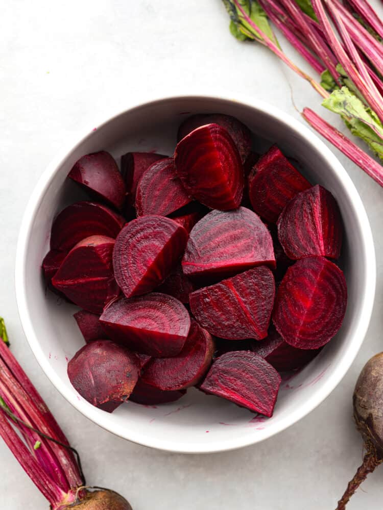 Top-down view of chopped beets in a white bowl.