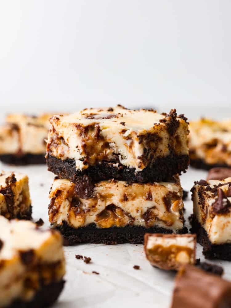 Closeup of 2 Snickers cheesecake bars stacked on top of each other.