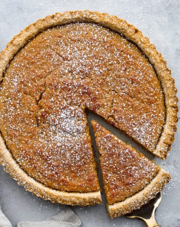 Treacle tart with a slice being lifted out of the tart with a pie scoop.
