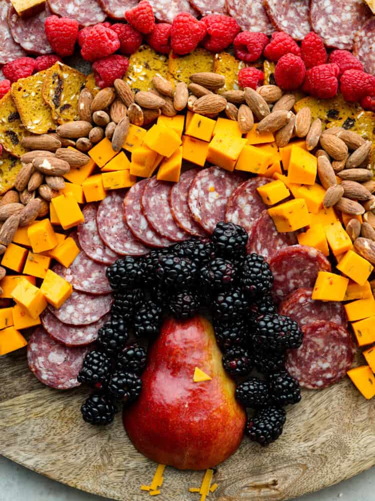 A close up view of the pear shaped turkey body.  Fruit, salami, cheese, crackers, and nuts surround the turkey body.