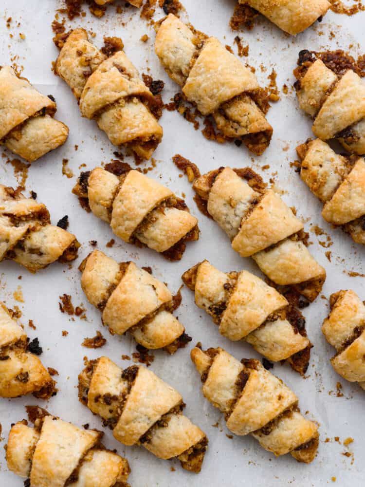 Top view of many baked rugelach cooling on parchment paper.