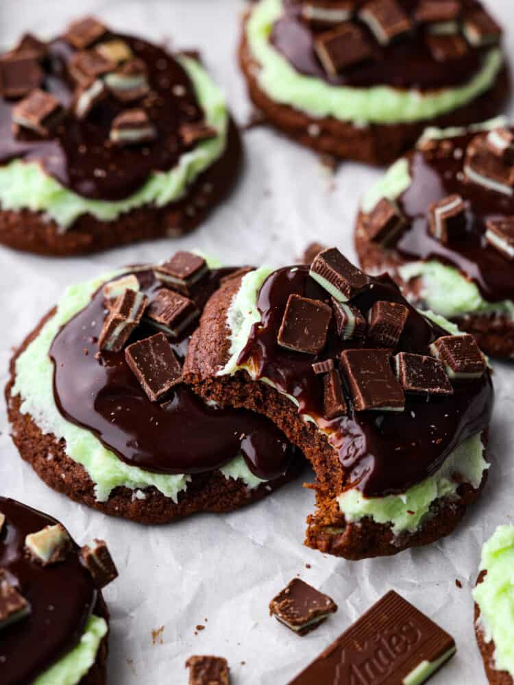 Andes mint chocolate cookies on parchment paper, and one of the cookies has a bite taken out of it.