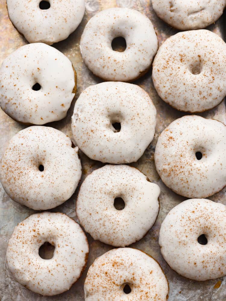 Top-down view of baked apple cider donuts on parchment paper.