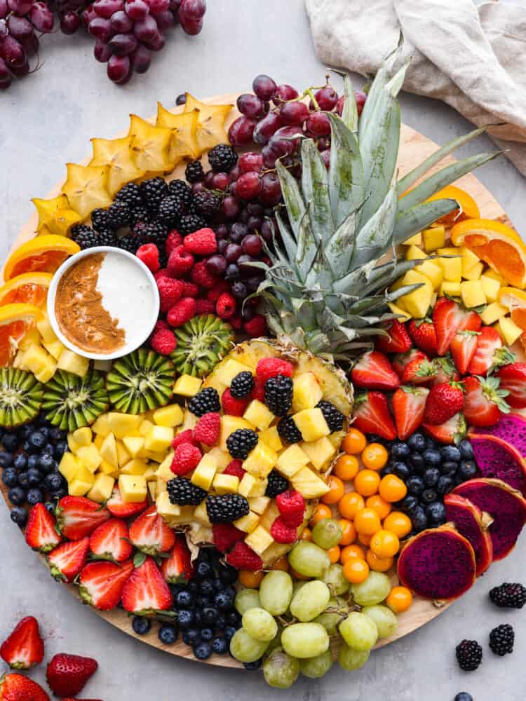 Overhead view of the fruit charcuterie board. A tan kitchen towel and extra fruit is scattered around the board.
