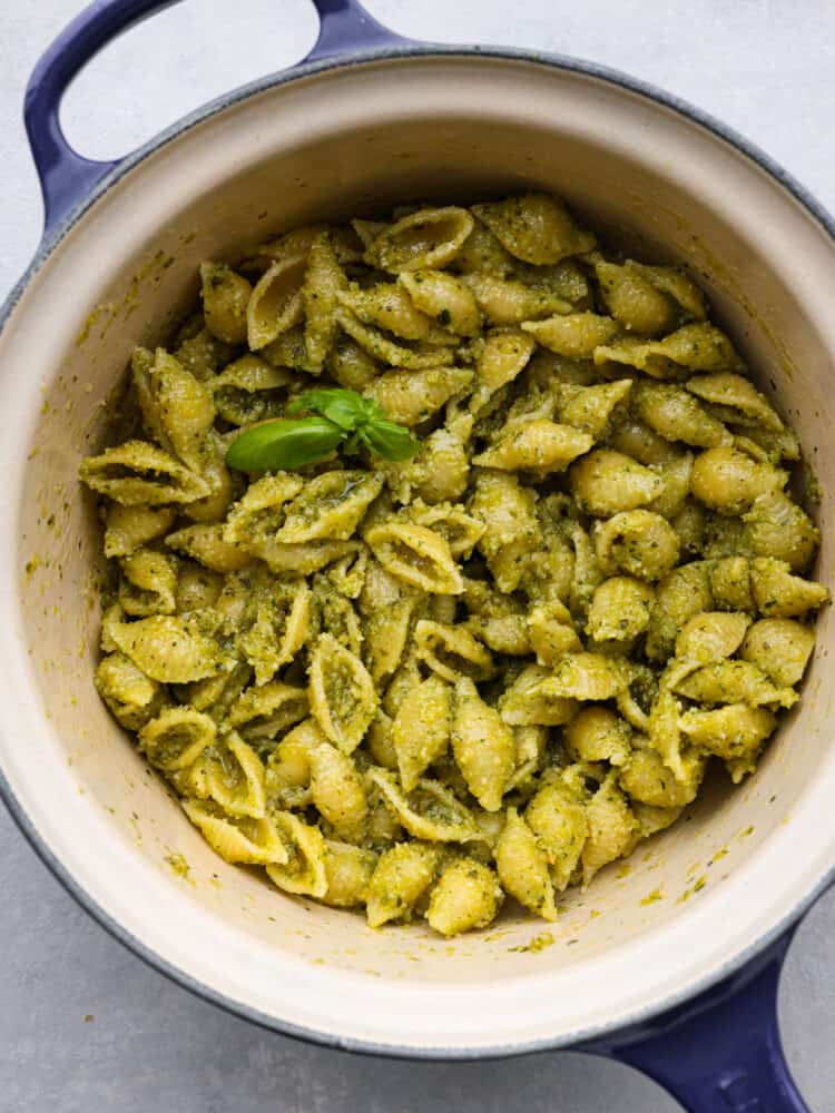 Shell pasta tossed with pesto in a white and blue skillet.