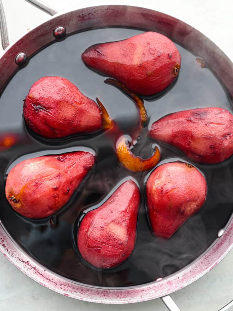 Pears in the red wine sauce with steam coming off of it.