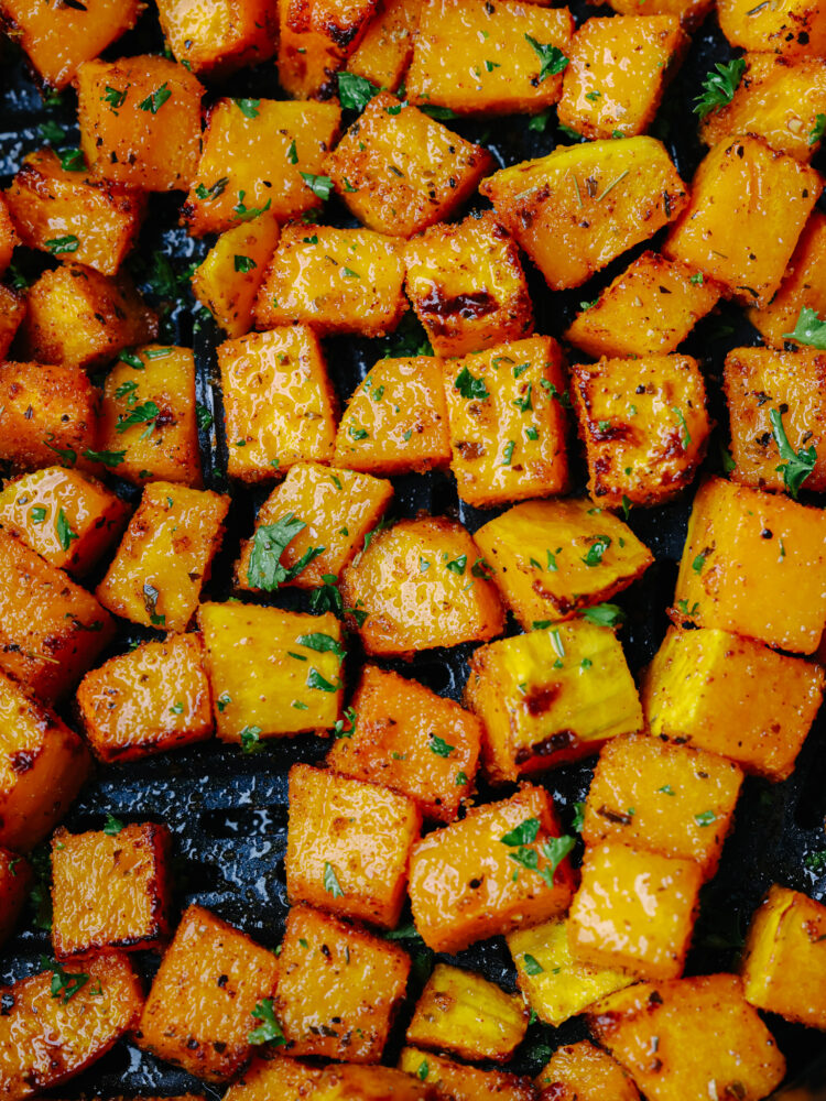 Close up view of air fryer butternut squash garnished with fresh parsley.