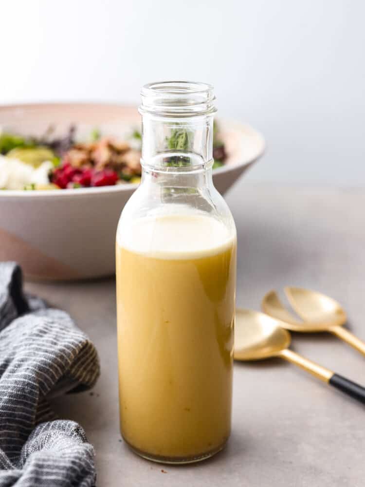 Champagne vinaigrette in a glass jar with a salad in the background.