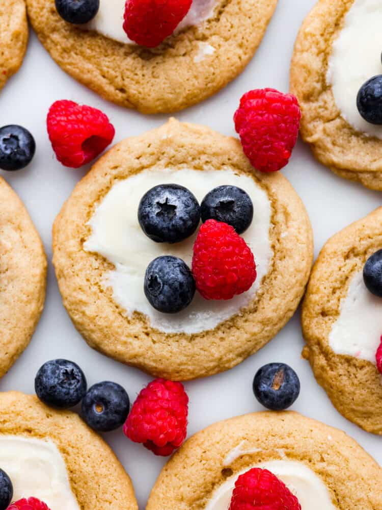 A zoomed in shot of a cheesecake cookie topped with blueberries and raspberries. 