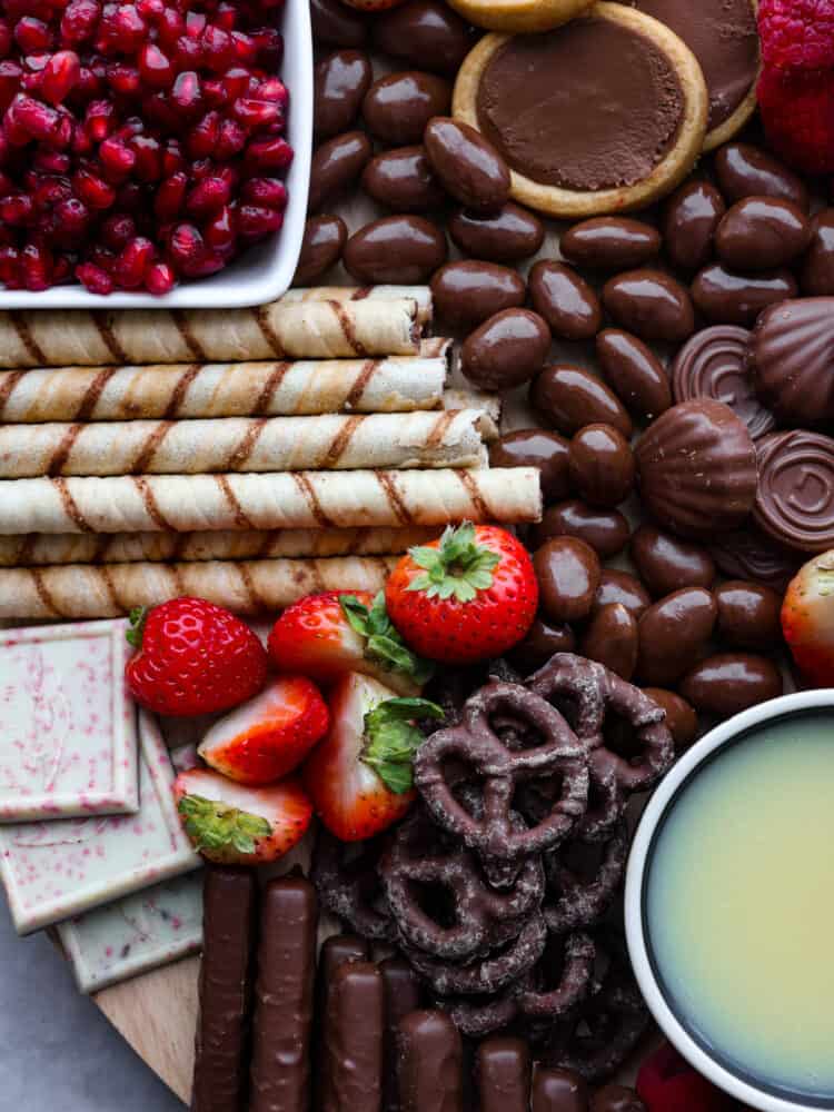 Close up photo of the chocolate charcuterie board. Cookies, chocolate almonds, and fruit are scattered on the board.