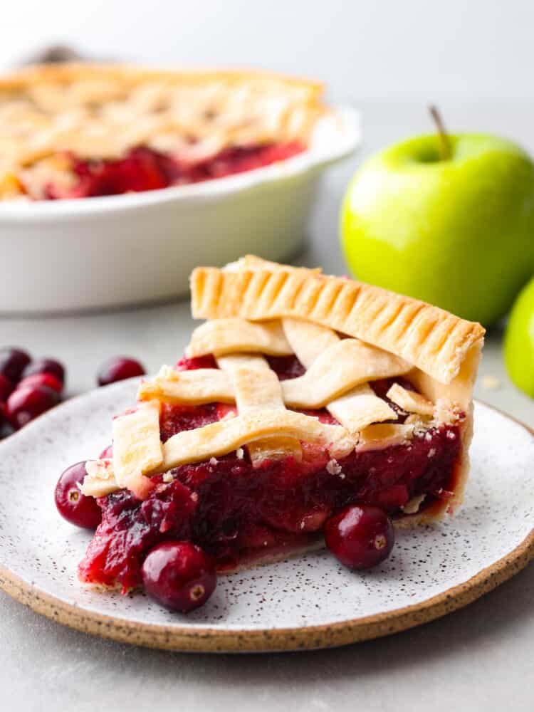 A slice of cranberry apple pie on a stoneware plate.