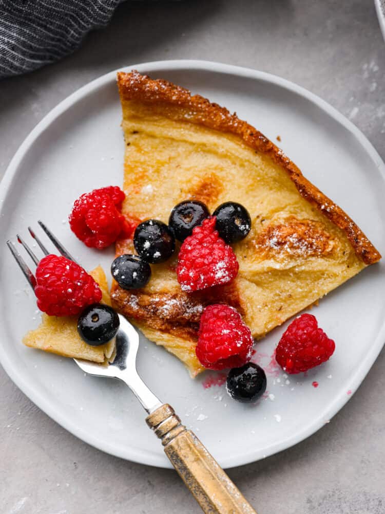 A slice of a Dutch baby on a white plate.