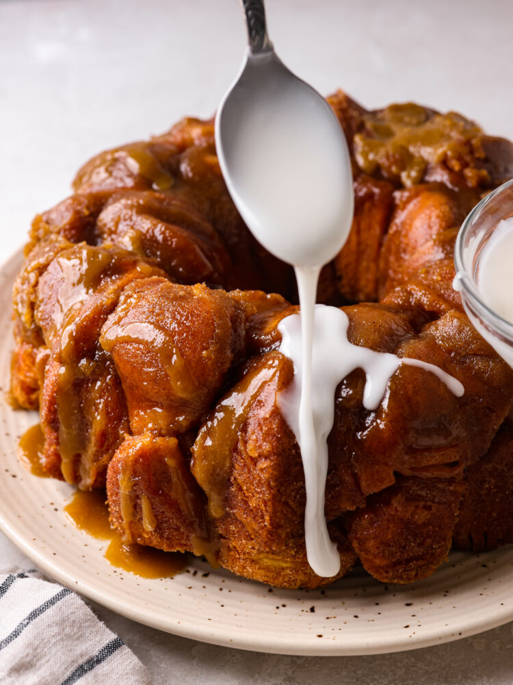 Powdered sugar glaze being drizzled on top of monkey bread.