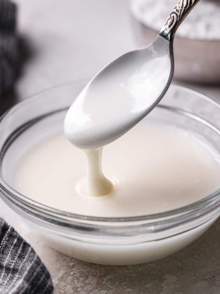 Powdered sugar glaze on a spoon and in a glass bowl.