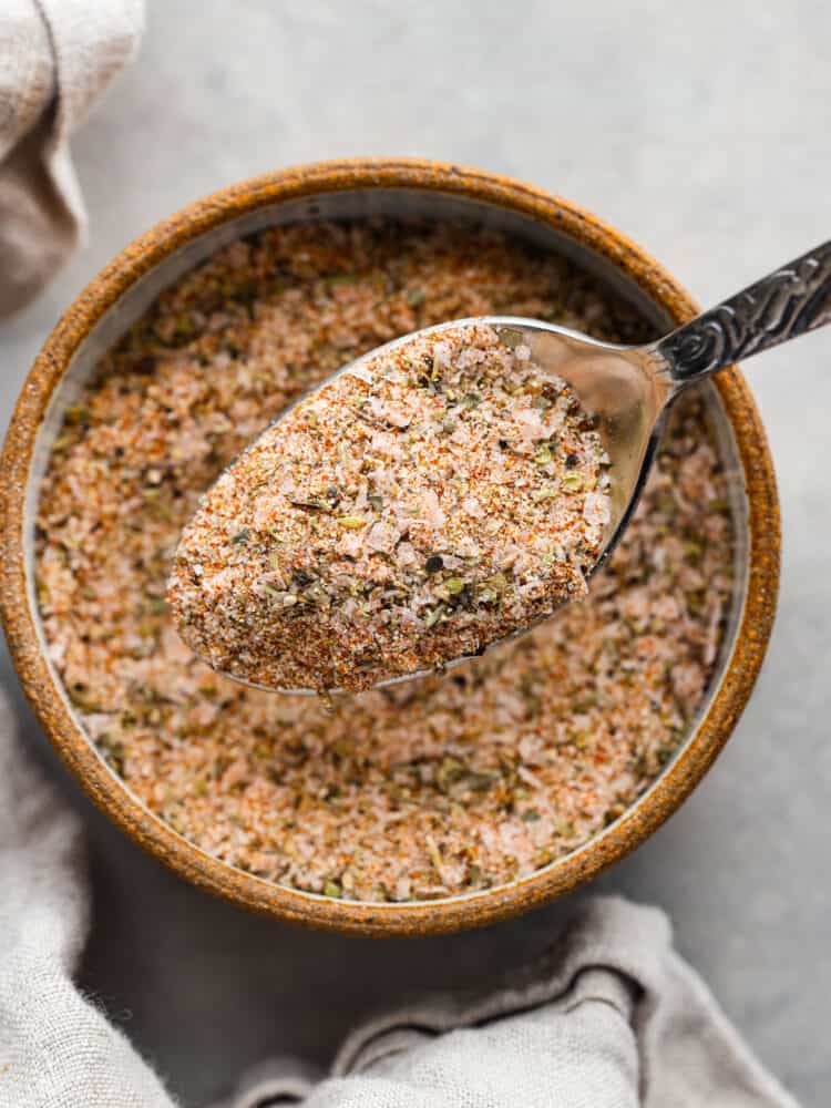 Prime rib rub in a spoon above the bowl of seasoning.