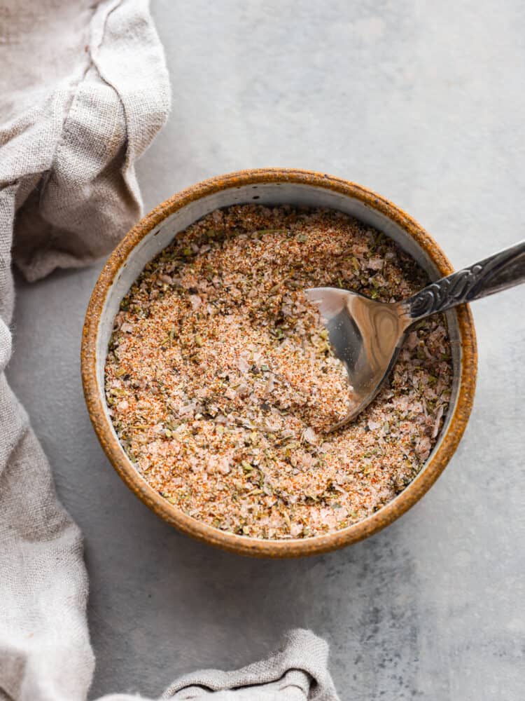 A bowl of prime rib rub with a metal spoon sticking in it.