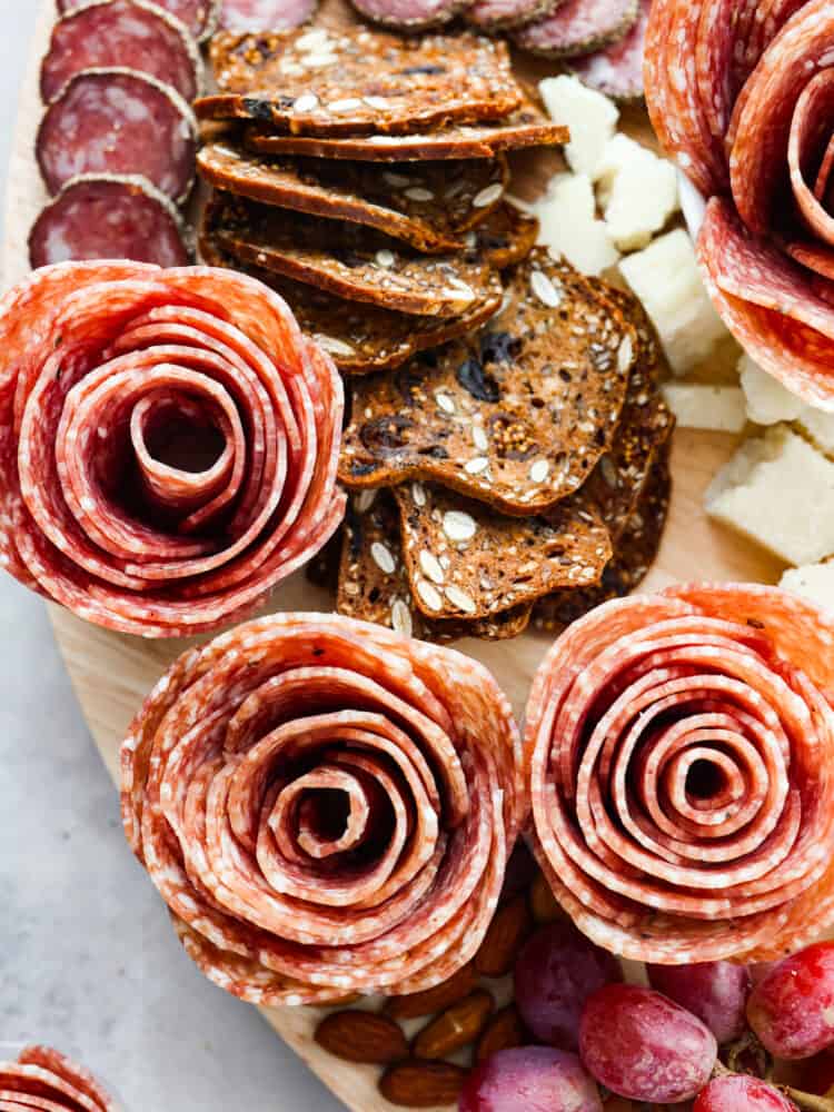 A close up of a charcuterie board with salami and crackers and cheese.