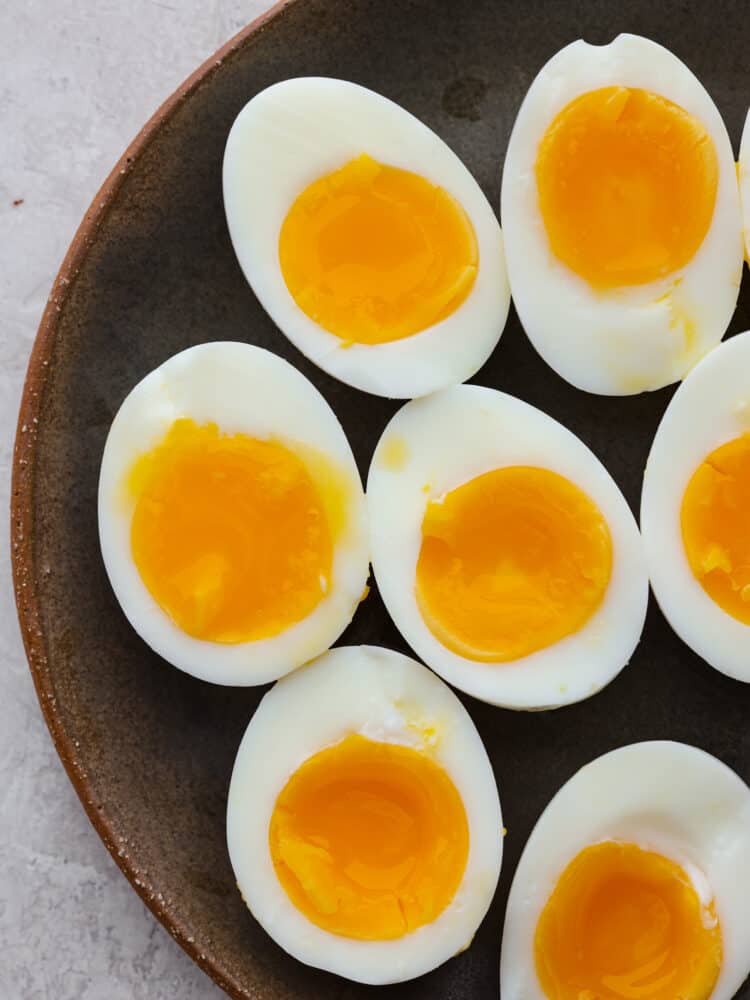 Soft boiled eggs on a dark plate cut in half so you can see the yolks.