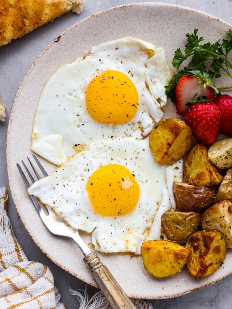 En tallrik mat med ägg, potatis och jordgubbar med en gaffel.