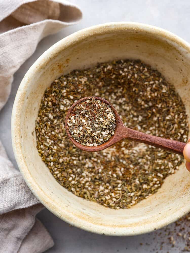 Seasoning in a bowl with a wooden spoon taking out a scoop.