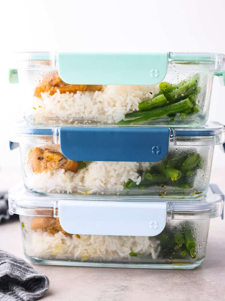 3 airtight containers filled with chicken and rice stacked on top of each other.