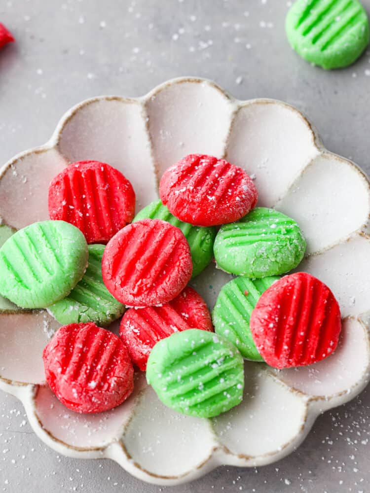 A close up of the red and green mints in a scalloped dish.