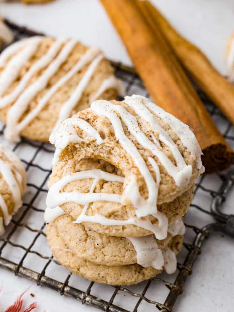 Closeup of eggnog cookies stacked on top of each other. One has a bite taken out of it.
