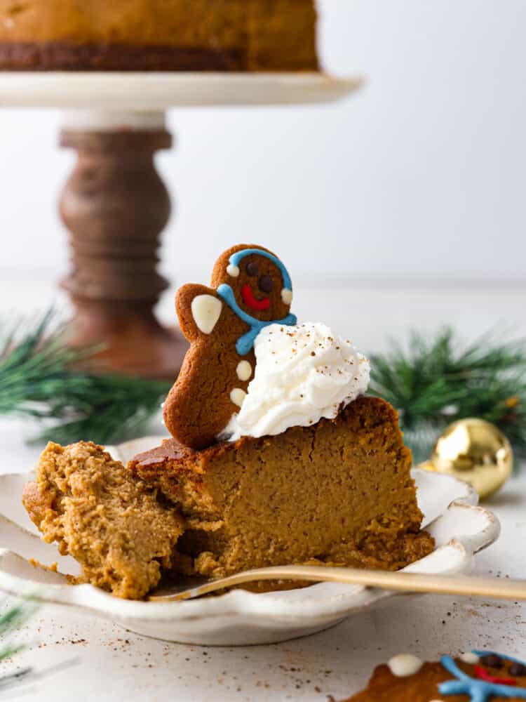 A slice of gingerbread cheesecake with a slice taken out of it with a cheesecake behind it.