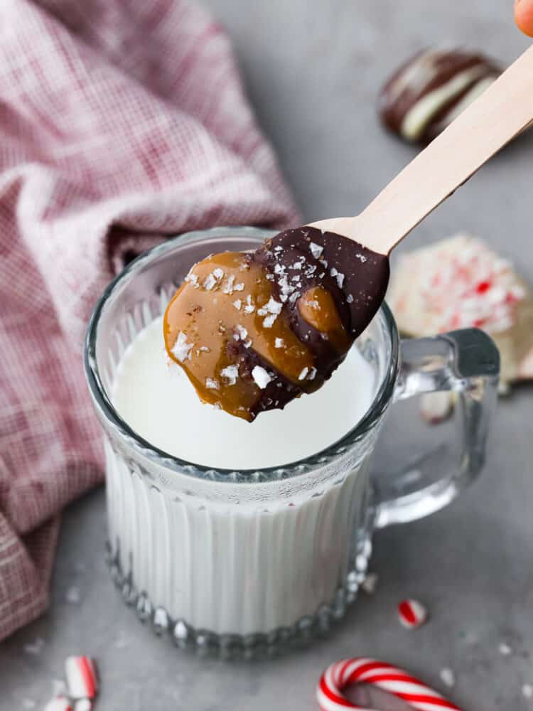 Cam bir kupada sütün üzerinde süzülen sıcak çikolata kaşığı.