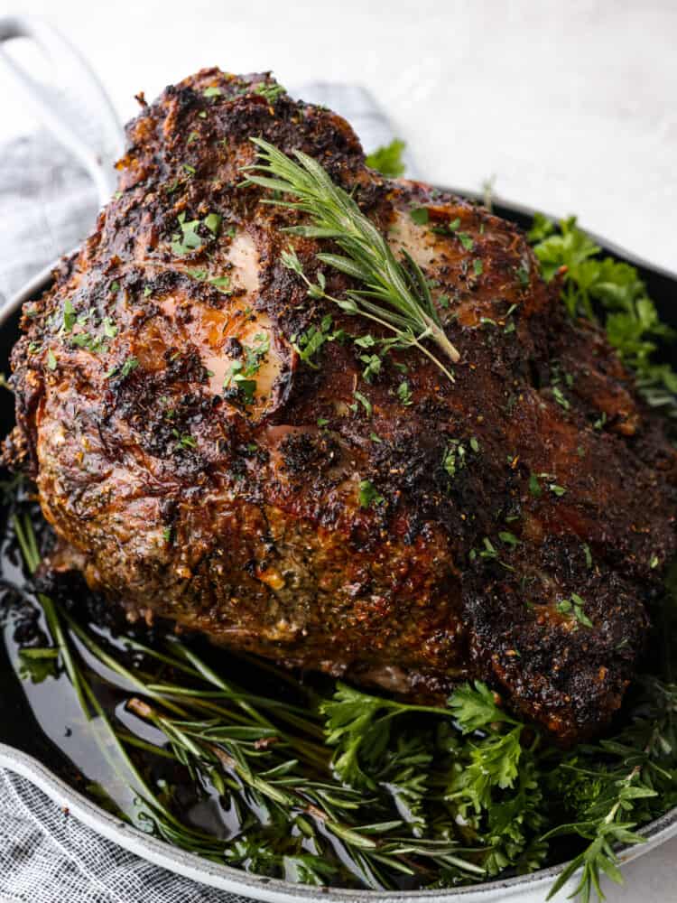 A cooked prime rib garnished with herbs.