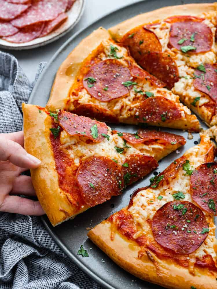 A close up picture of a slice being pulled away by a hand.