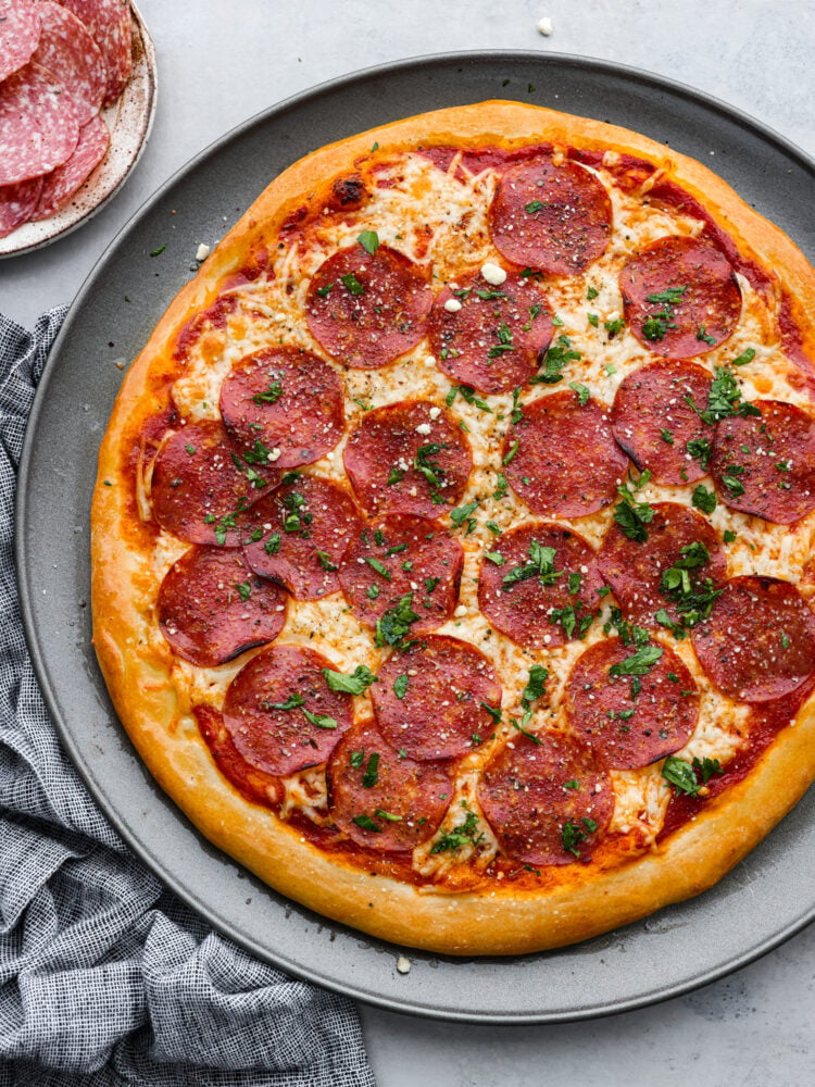 Una pizza intera al salame su un piatto grande.