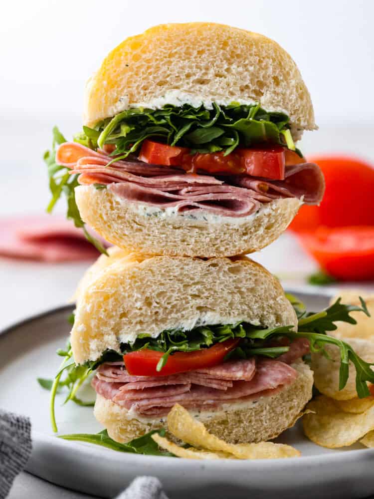 A salami sandwich cut in half and stacked on top of each other.