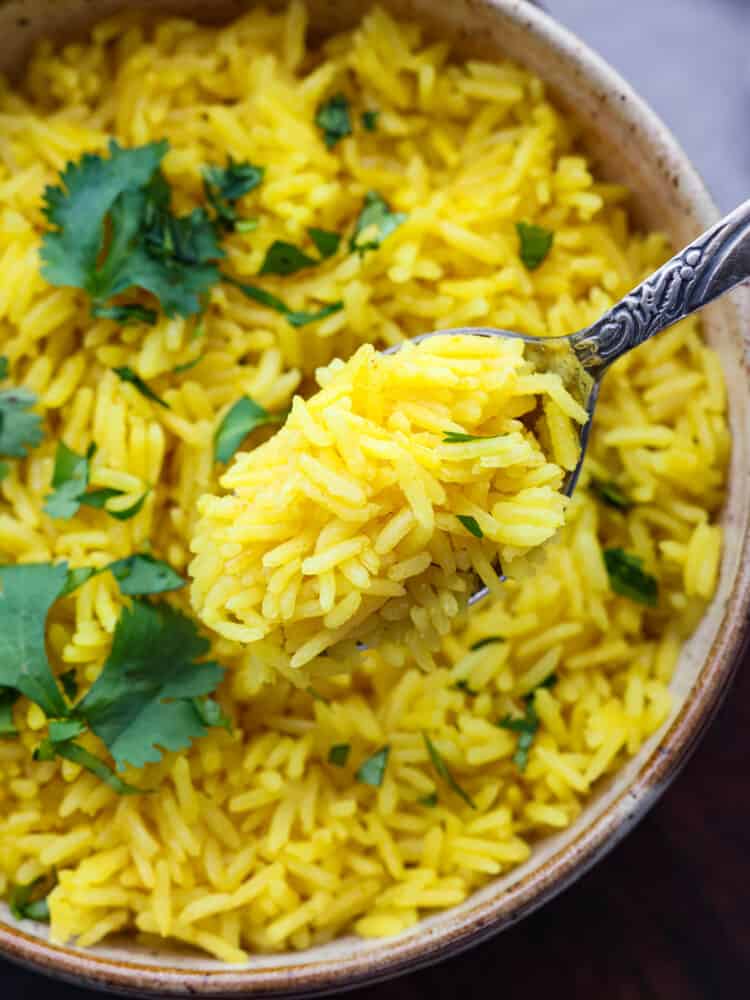 Closeup of yellow rice on a metal spoon.