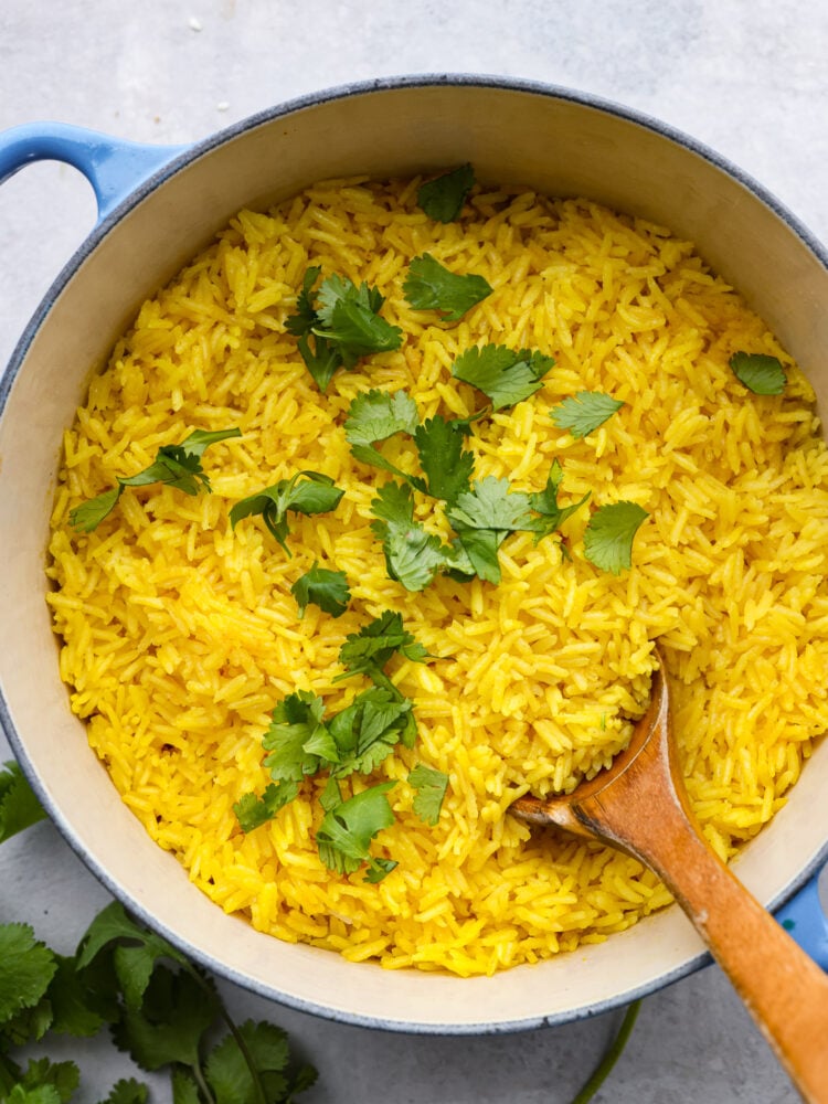 Top-down view of yellow rice in a white and blue skillet, garnished with cilantro.