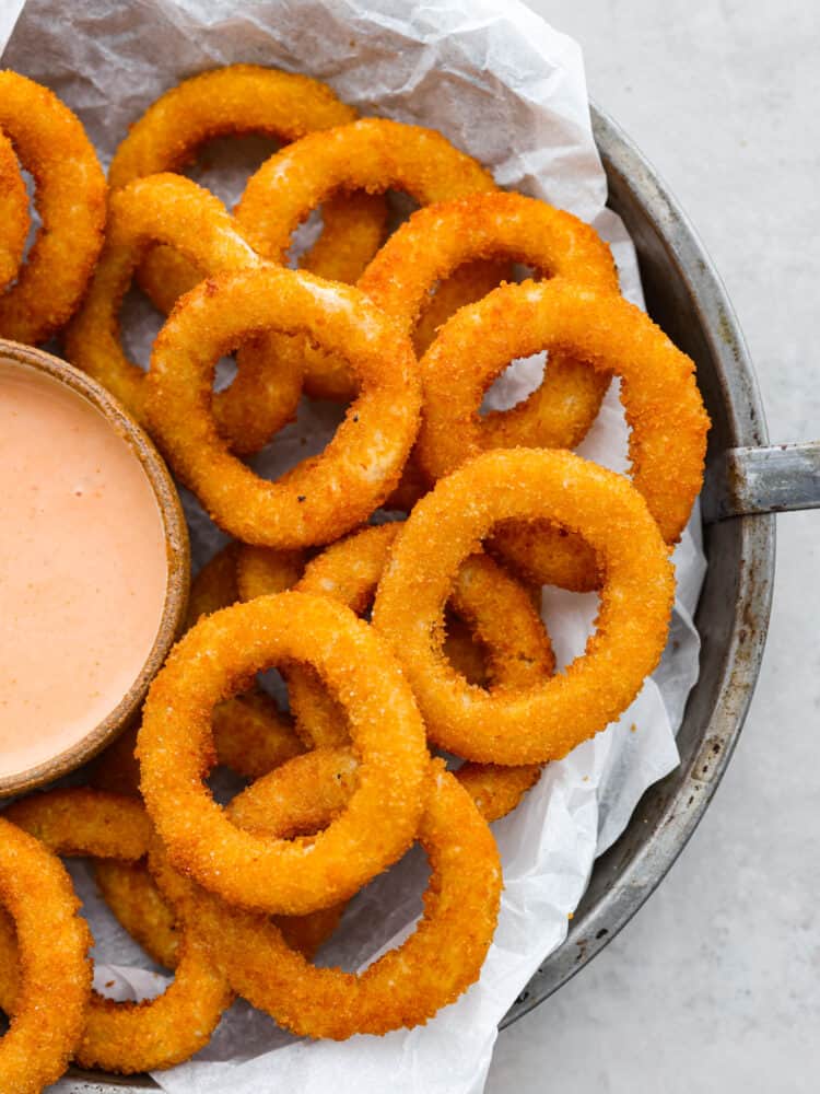 Air fryer frozen onion rings on a plate with parchment paper.